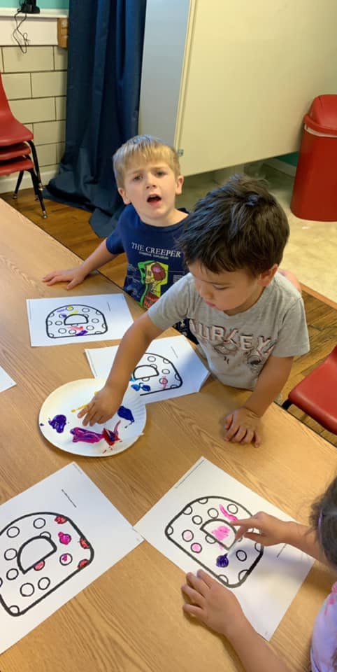 Two children finger painting at a table