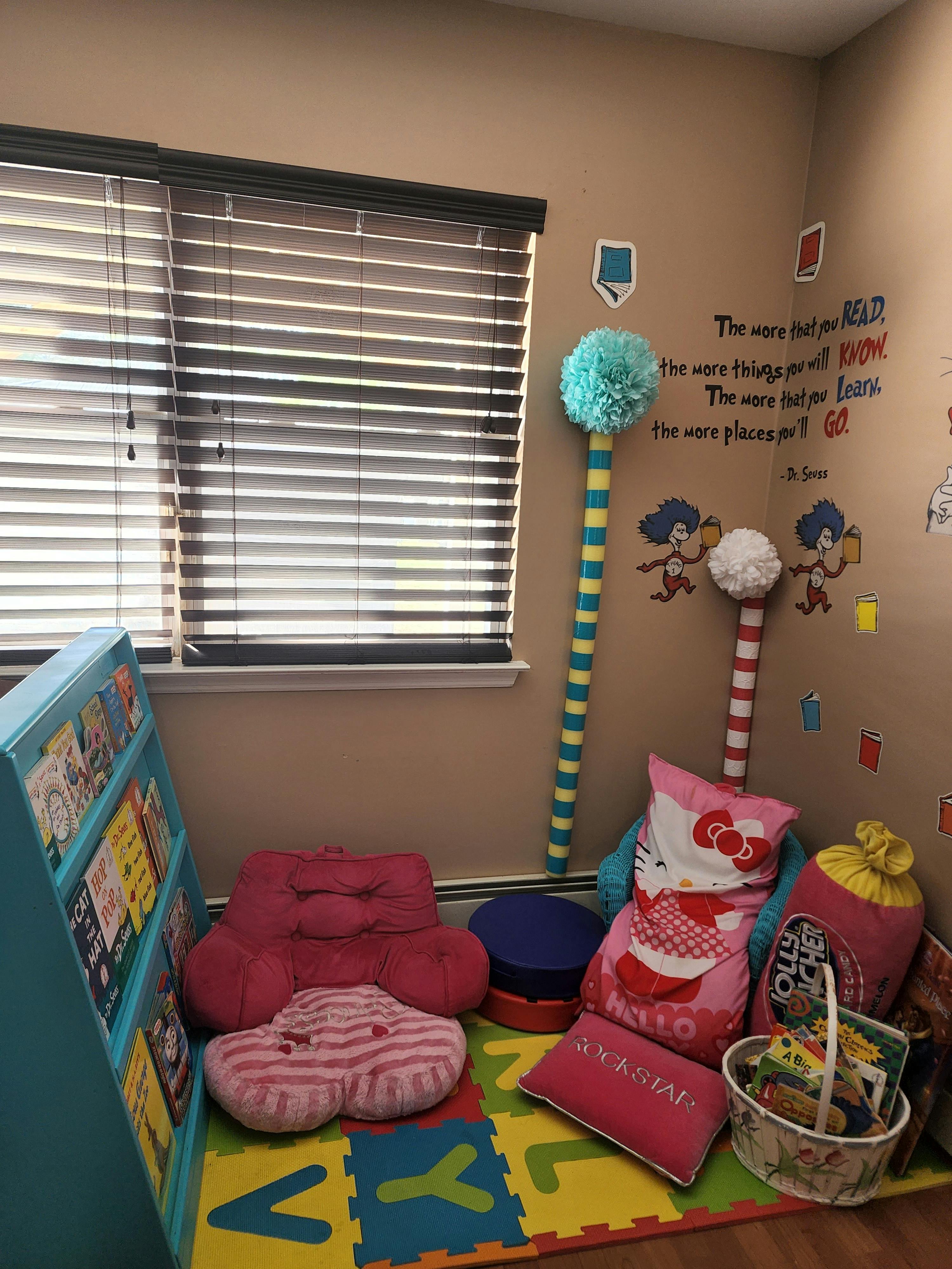 Children's reading nook with a bookshelf, floor cushions, and wall decorations