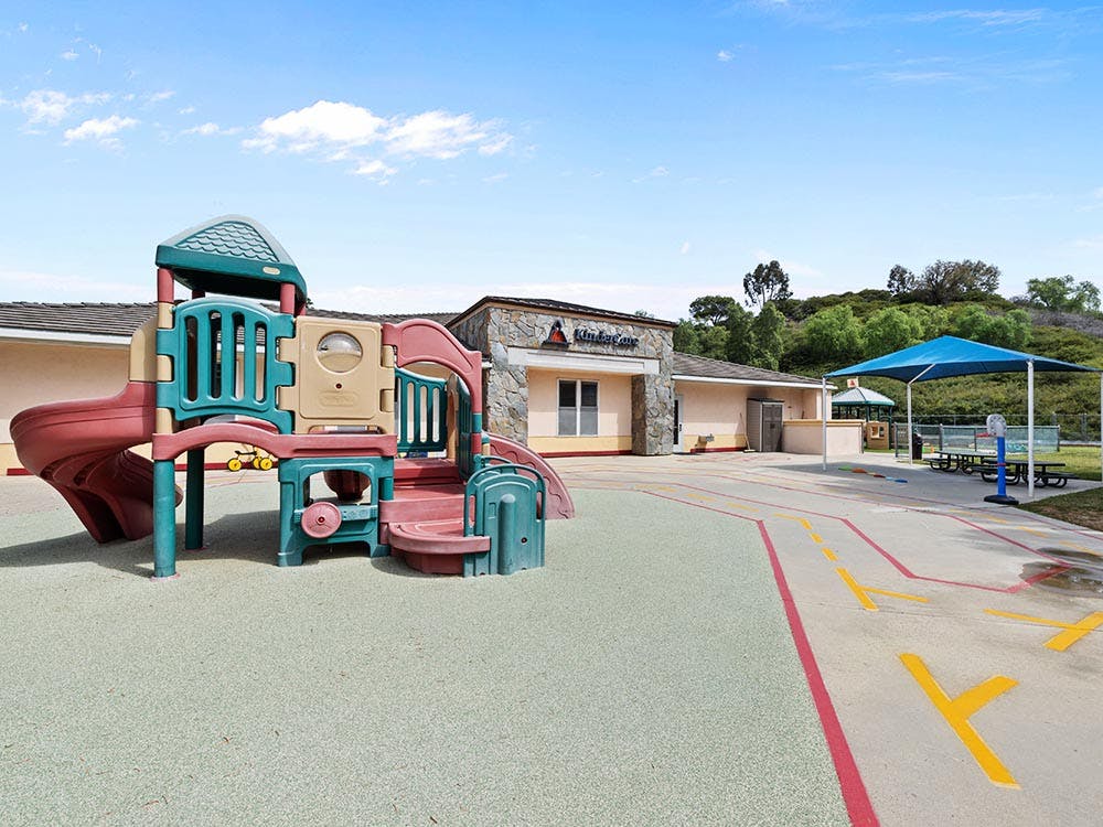 A playground with a plastic play structure, slides, and a shaded picnic area
