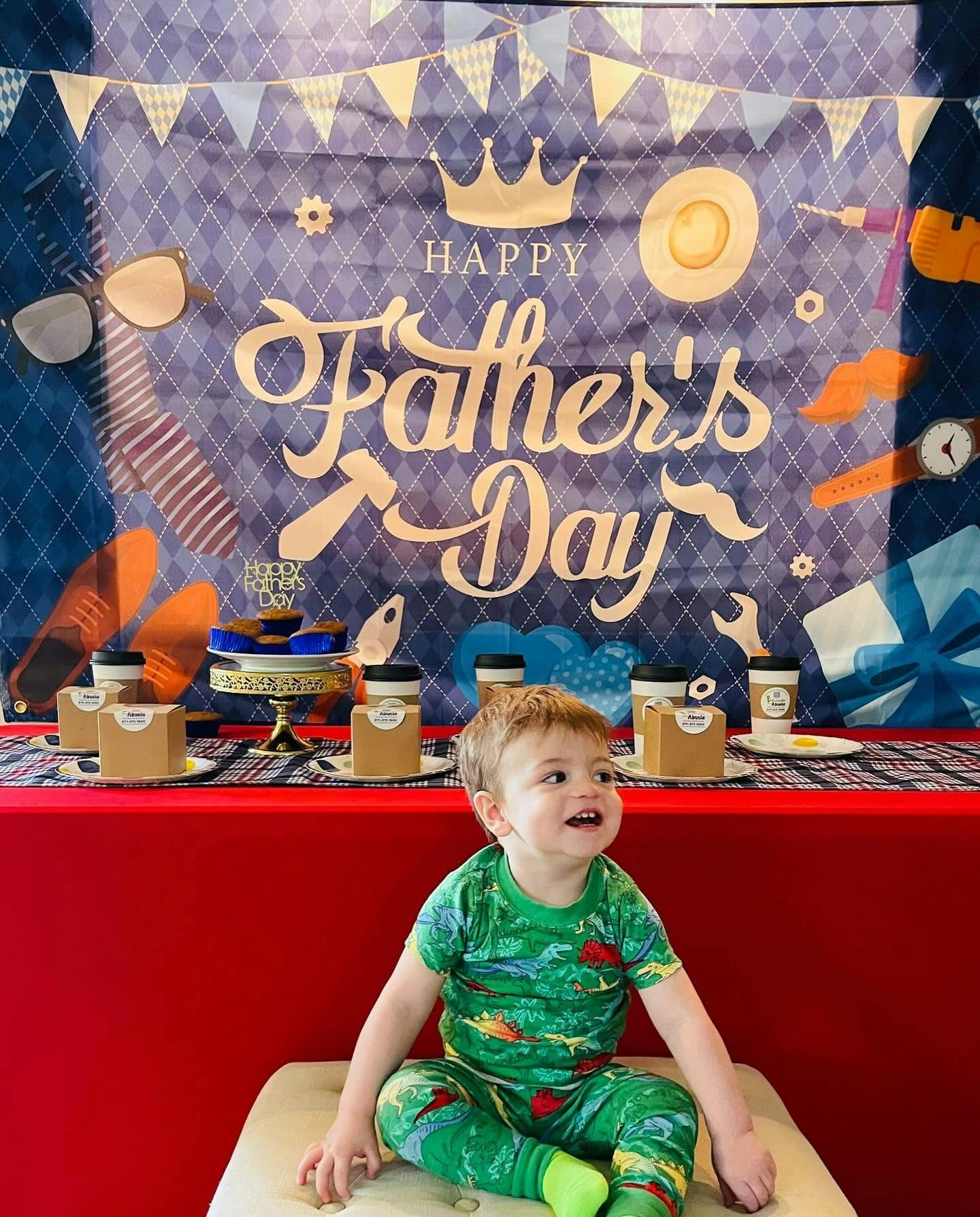 Child sitting on a bench in front of a Happy Father's Day party backdrop
