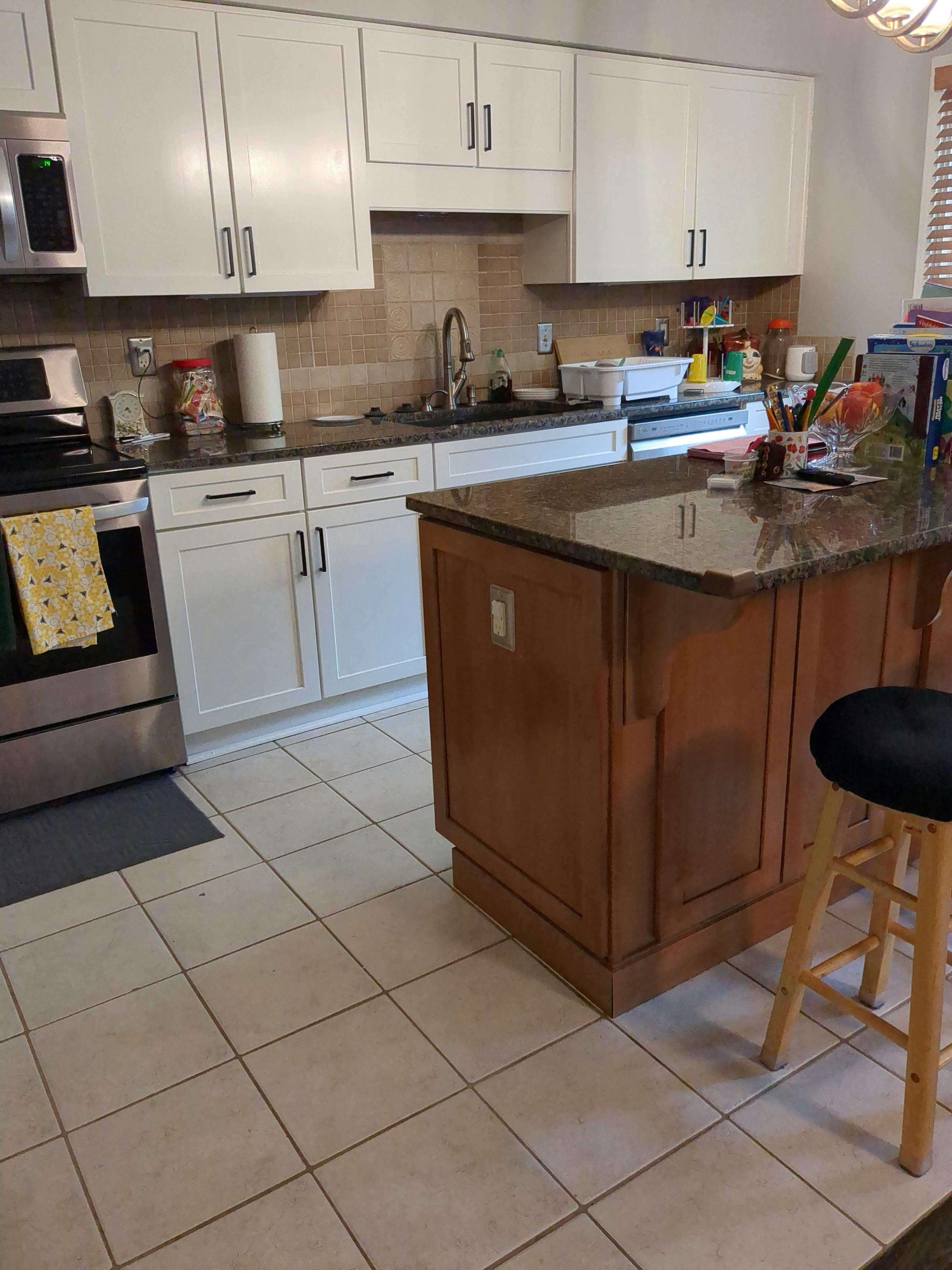 Kitchen interior with white cabinets, a brown kitchen island, and tiled floors