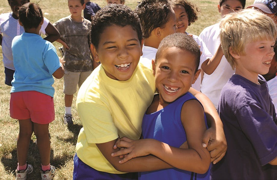 Two children embracing, with other children in the background