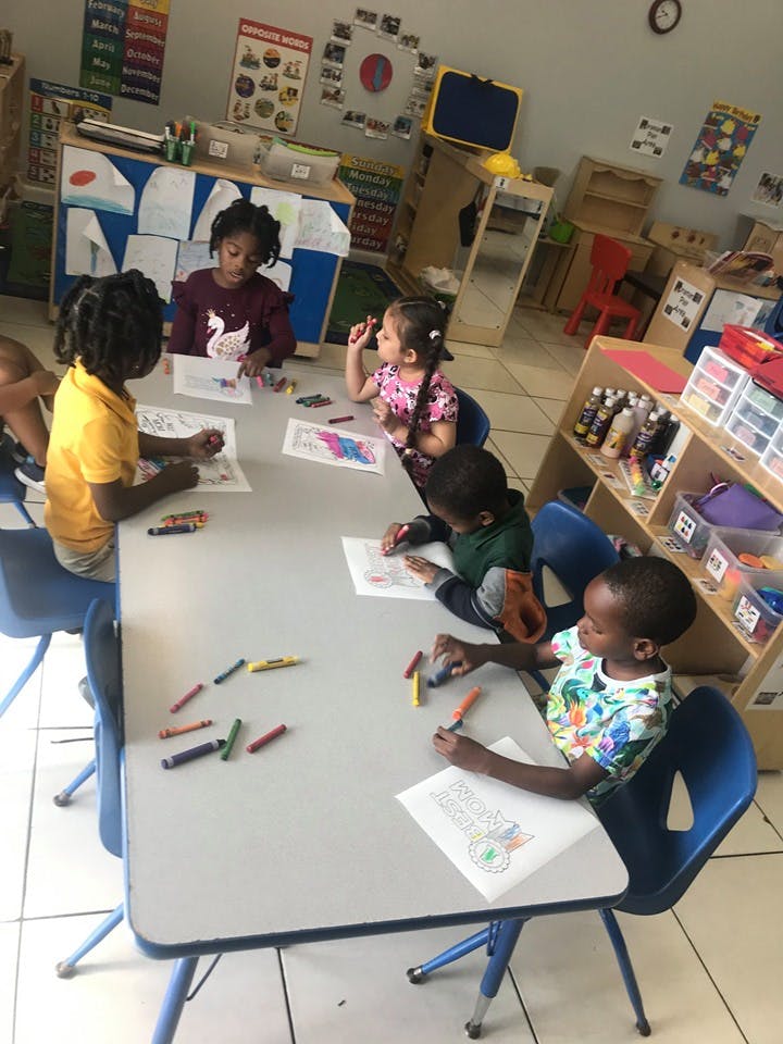 Children sitting at a table coloring with crayons and coloring pages