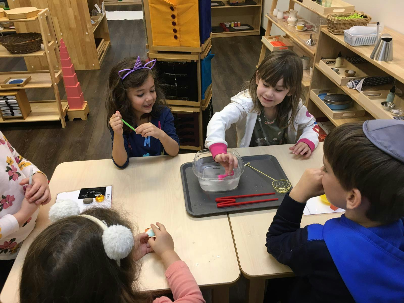Children at a table engaged in an activity with bowls and utensils