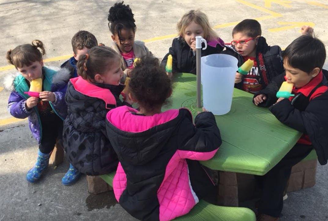 Children eating popsicles around a picnic table