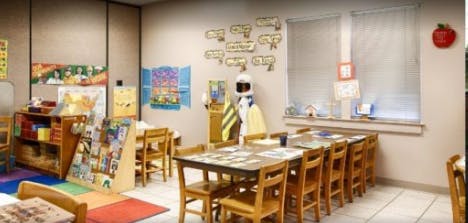 Classroom with small tables and chairs, bookshelves, and decorations