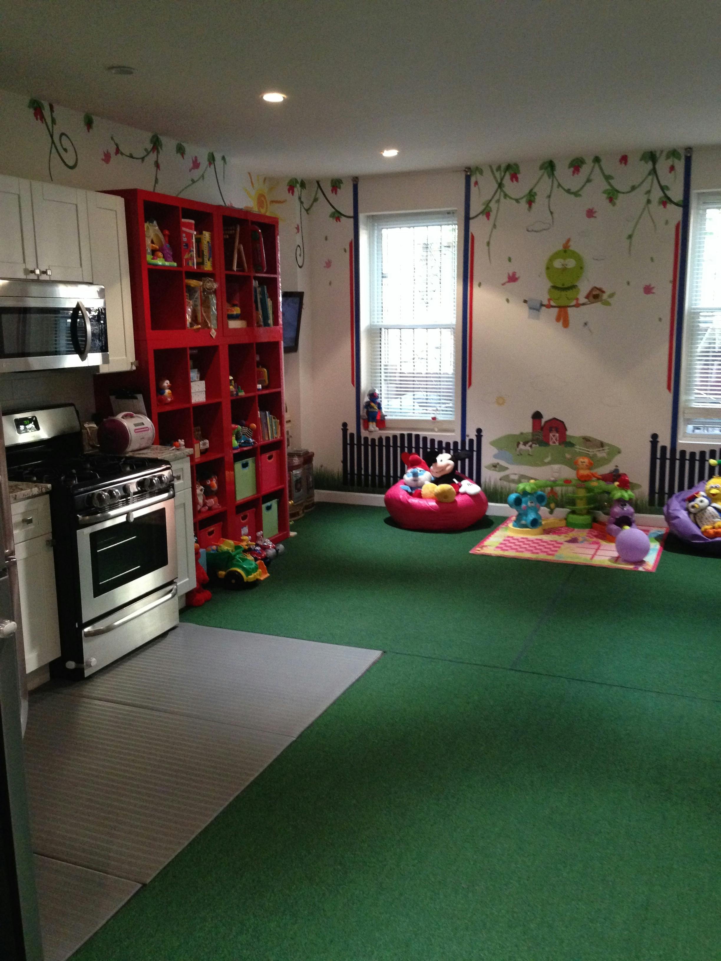 Kitchen area with a red bookshelf next to a green-carpeted play area