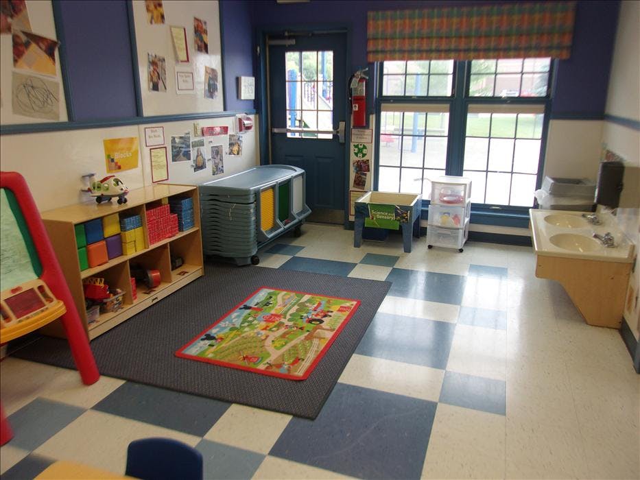 children's classroom with blue and white tiled floor, shelves of toys, and a small sink