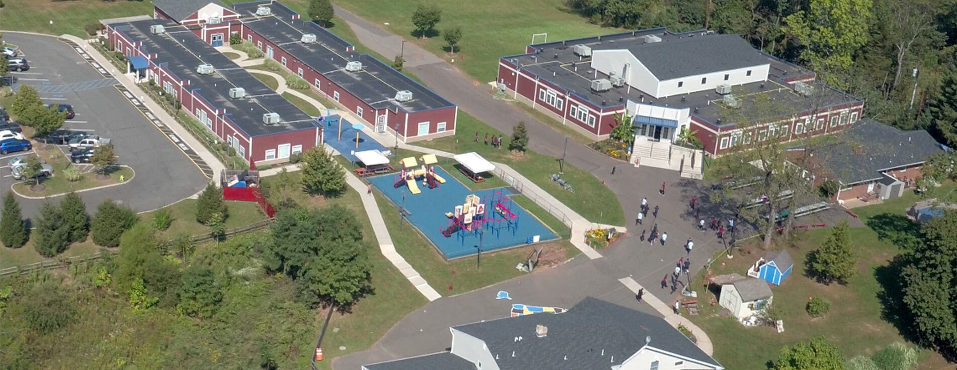Aerial view of a school campus with buildings, parking lot, and playground