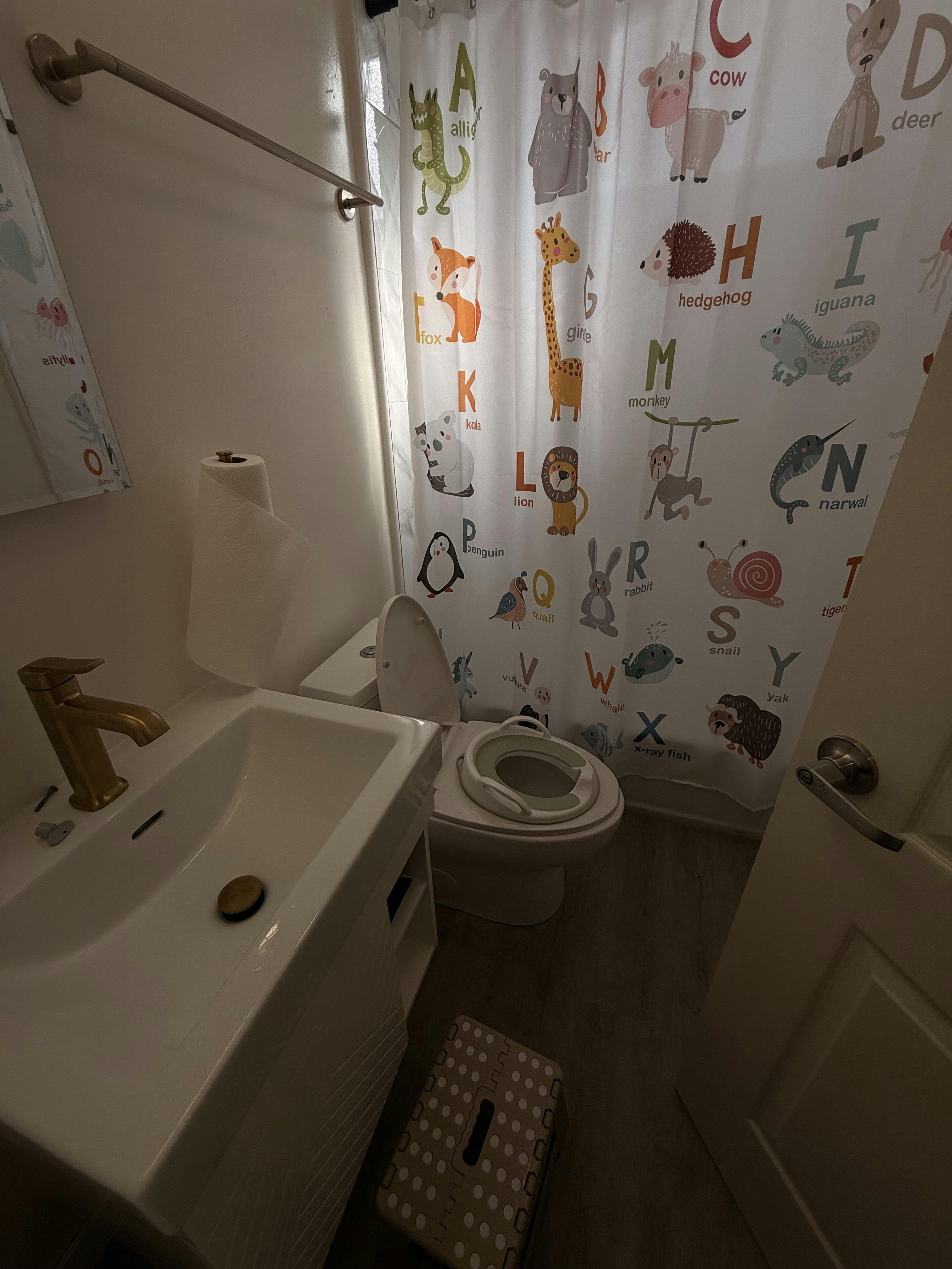 Small bathroom with toilet seat training cover and alphabet animal shower curtain