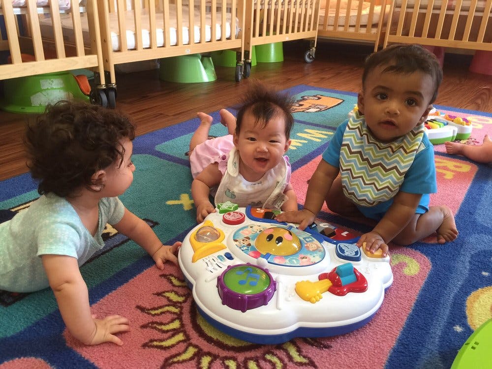 Three children playing with a toy on a colorful rug