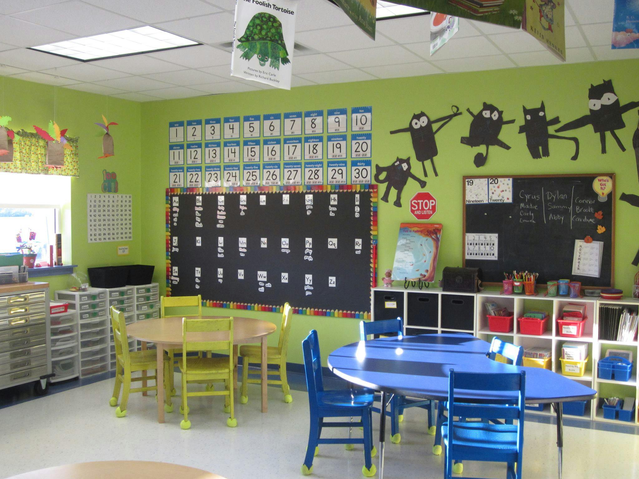 Classroom with green walls, round and oval tables, and chairs