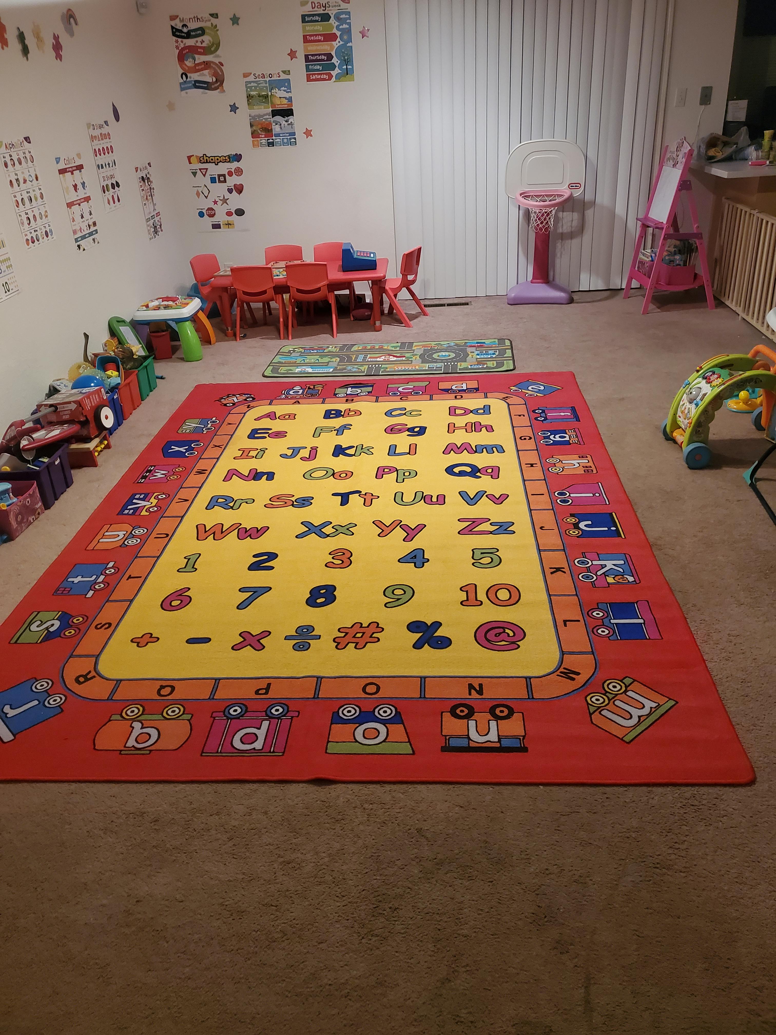 Playroom with alphabet rug, small red table and chairs, and toys