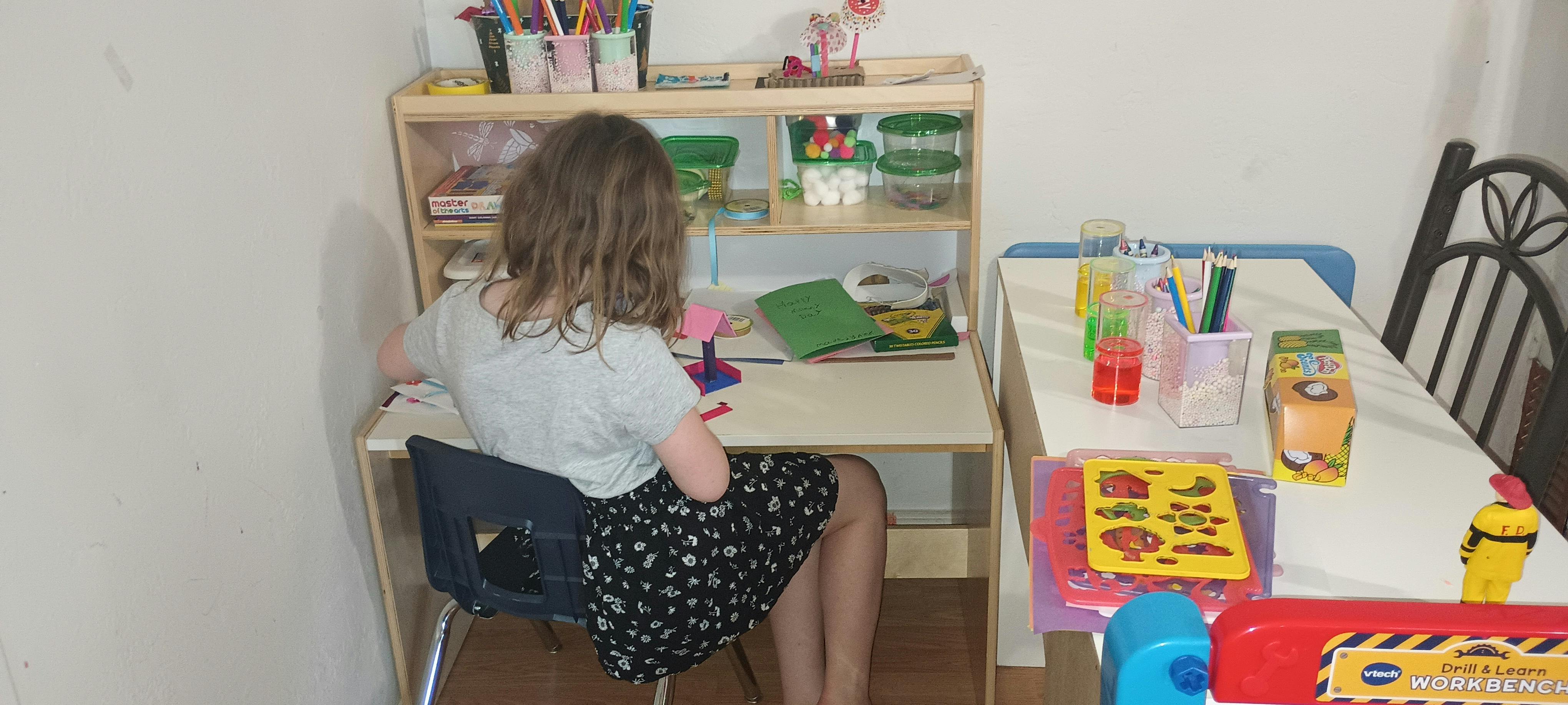 Child sitting at a desk with school supplies