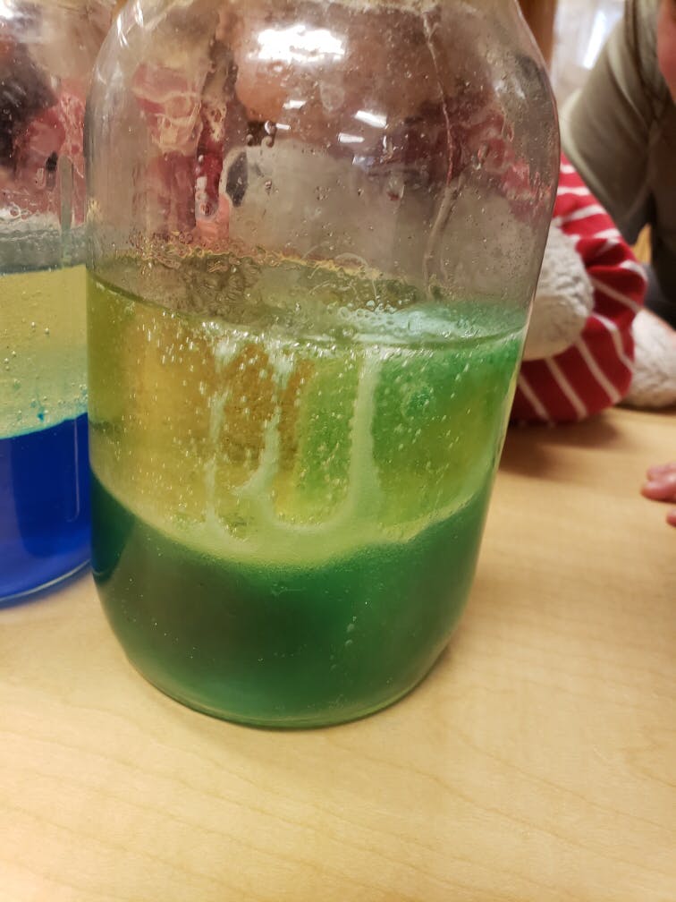 Green and yellow liquid in a clear jar, with bubbles