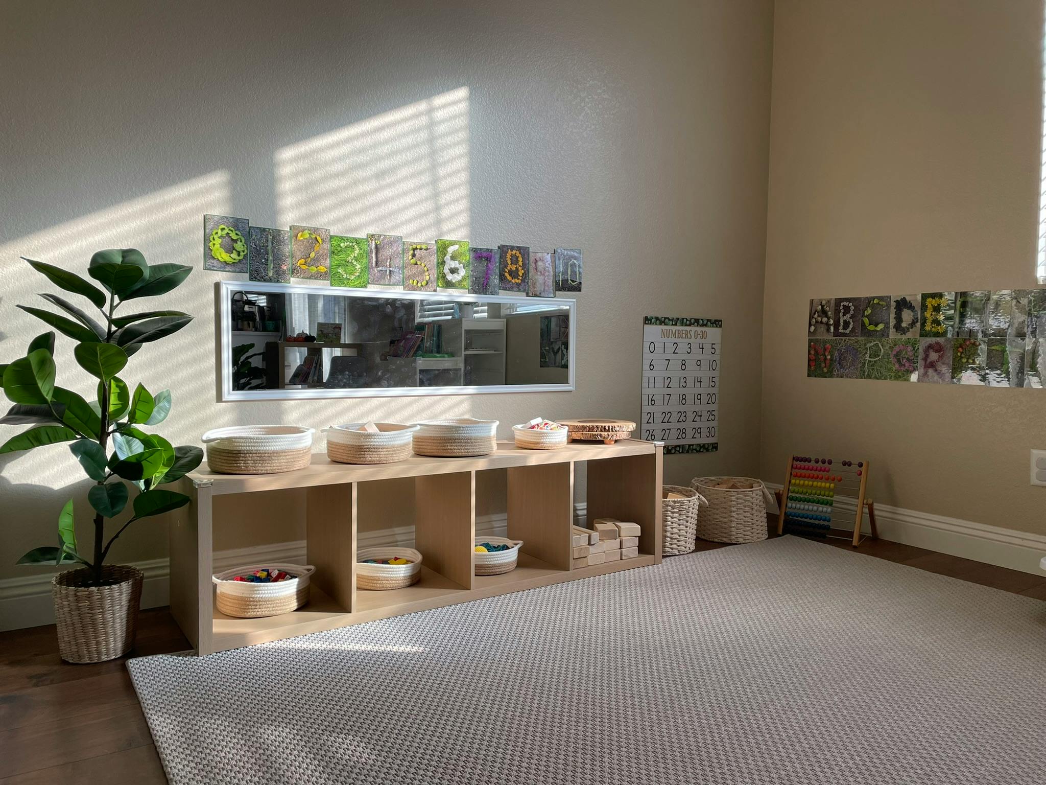 Classroom with wooden shelves, plant, and alphabet cards on the wall
