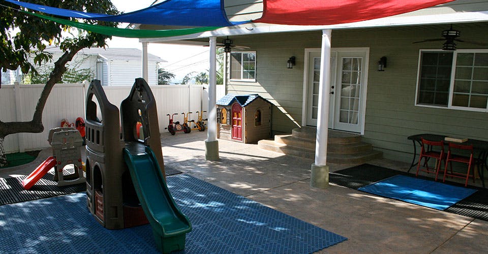 Outdoor play area with a slide, playhouse, and shaded patio