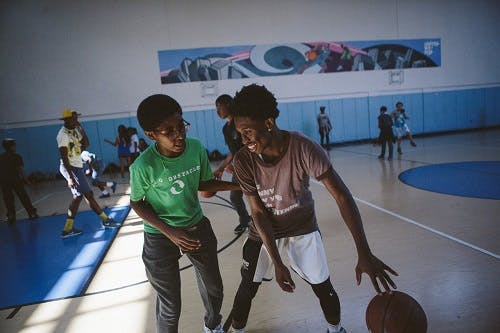 Two teens playing basketball in a gym