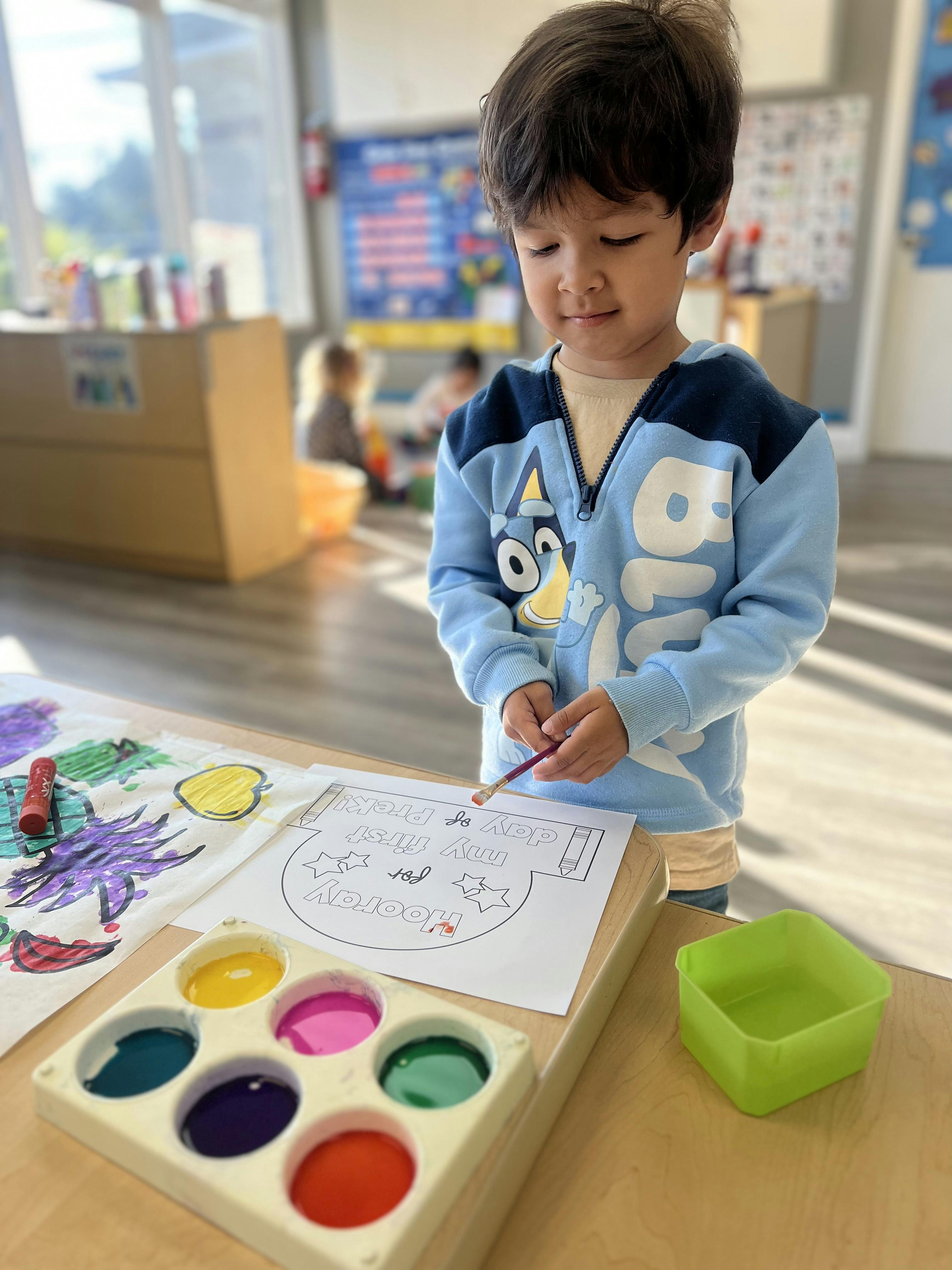 Child painting at a table in a classroom