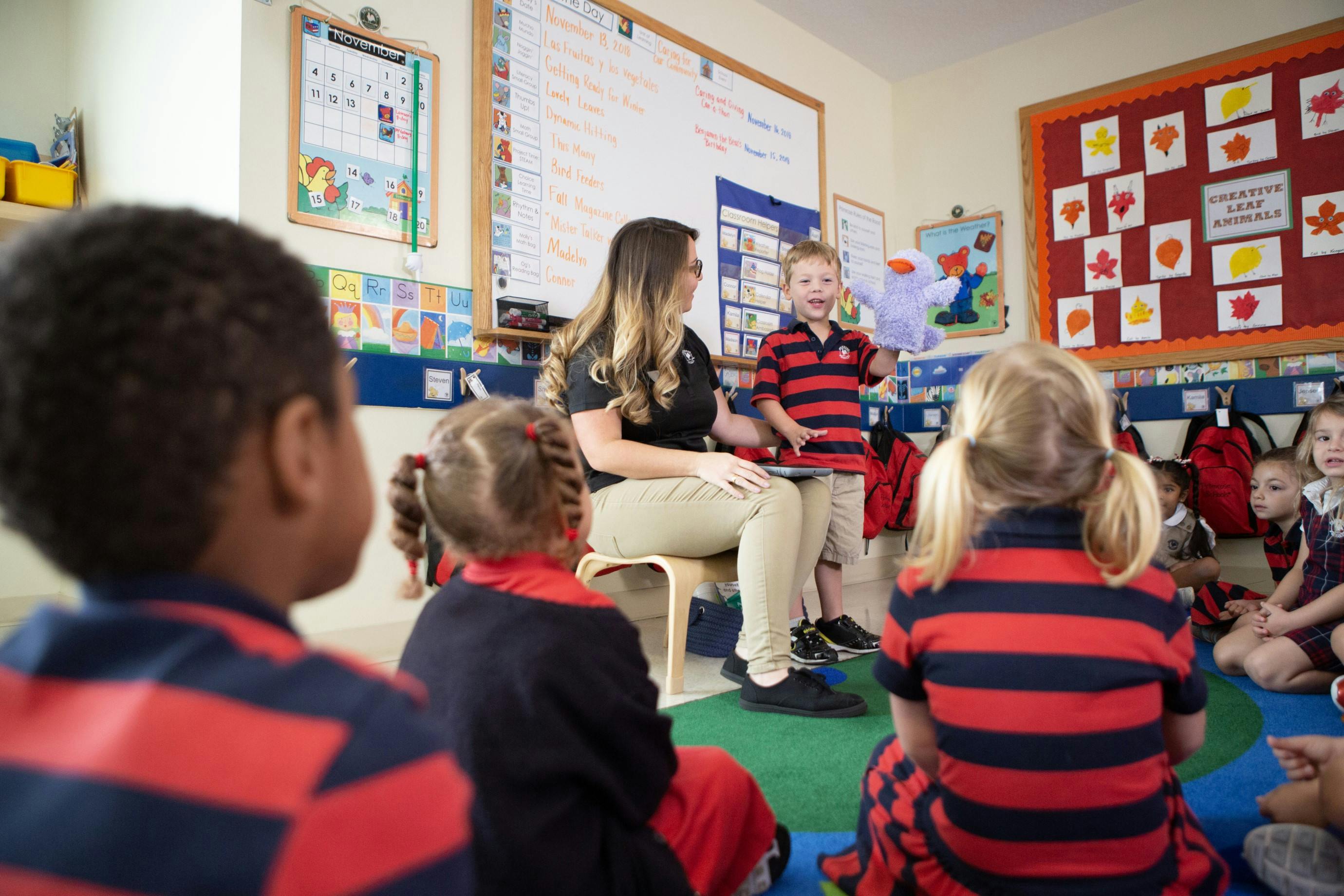 Adult and children in a classroom, one child standing and speaking