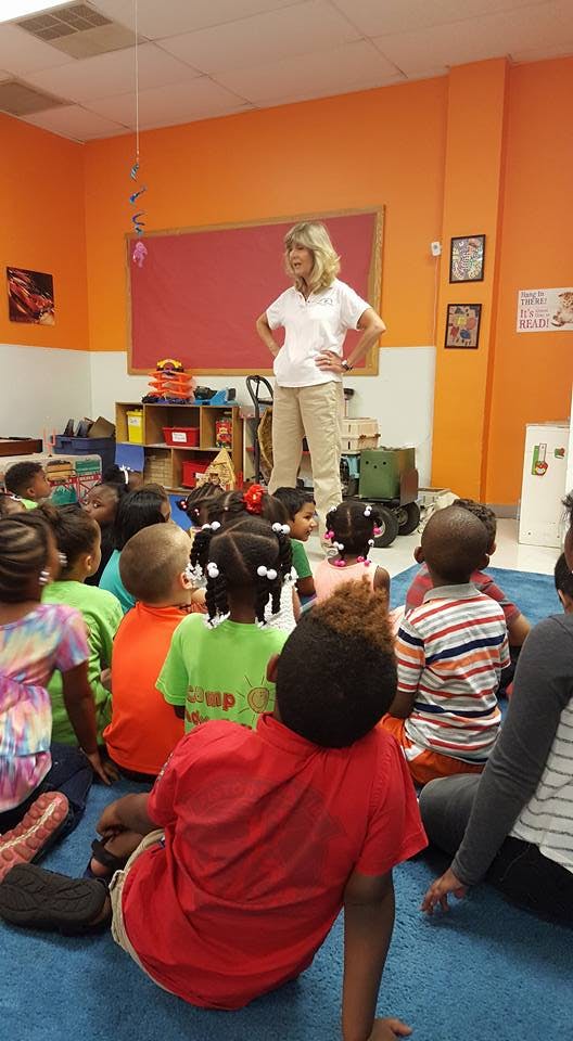 Person standing in front of a group of children sitting on the floor