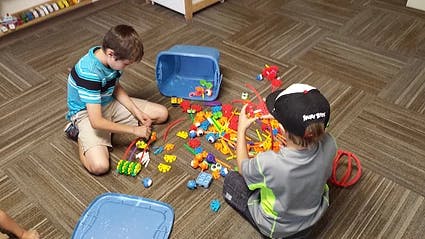 Two children playing with colorful building toys on the floor