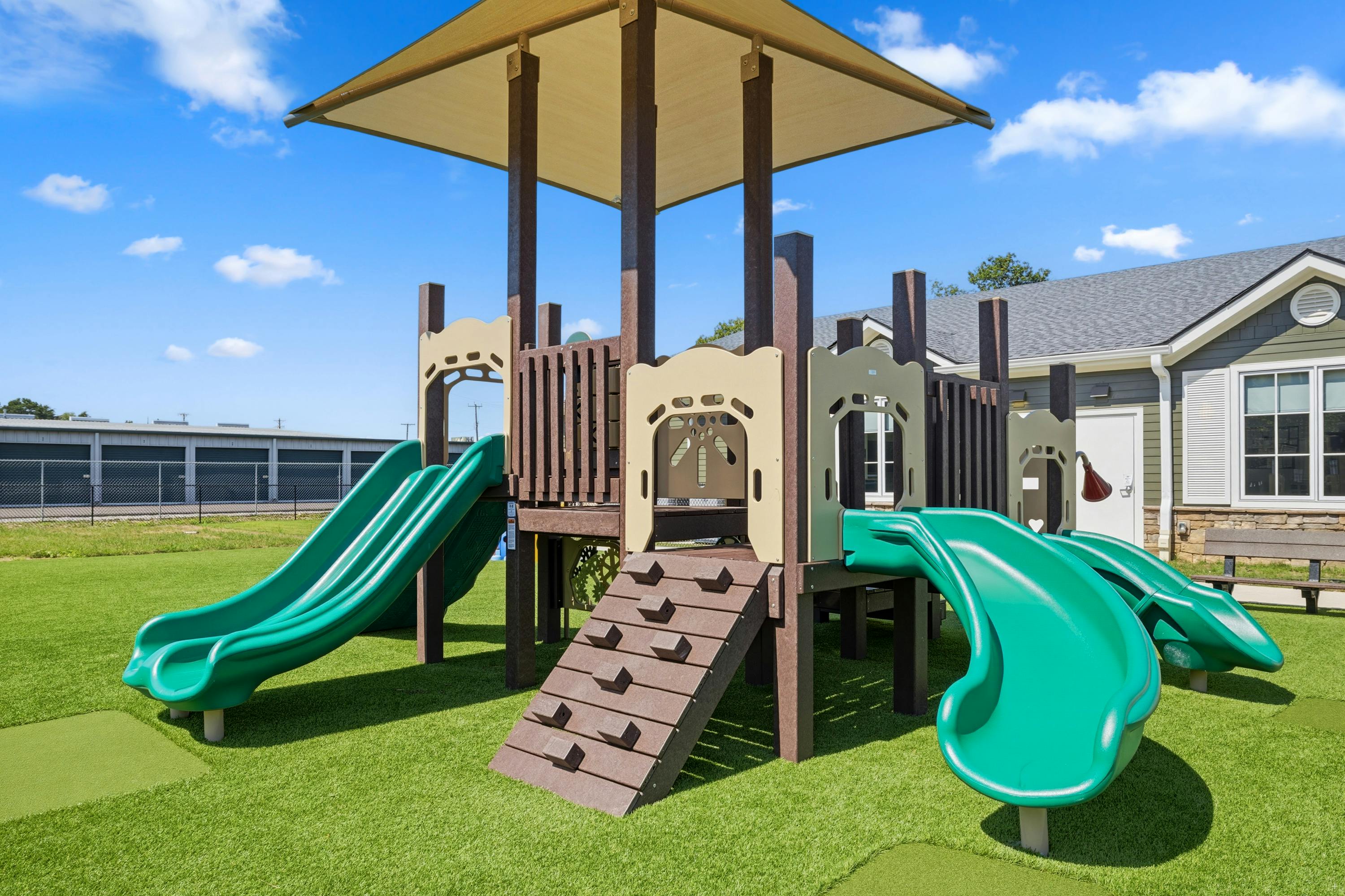 Playground structure with slides and a climbing ramp on artificial turf
