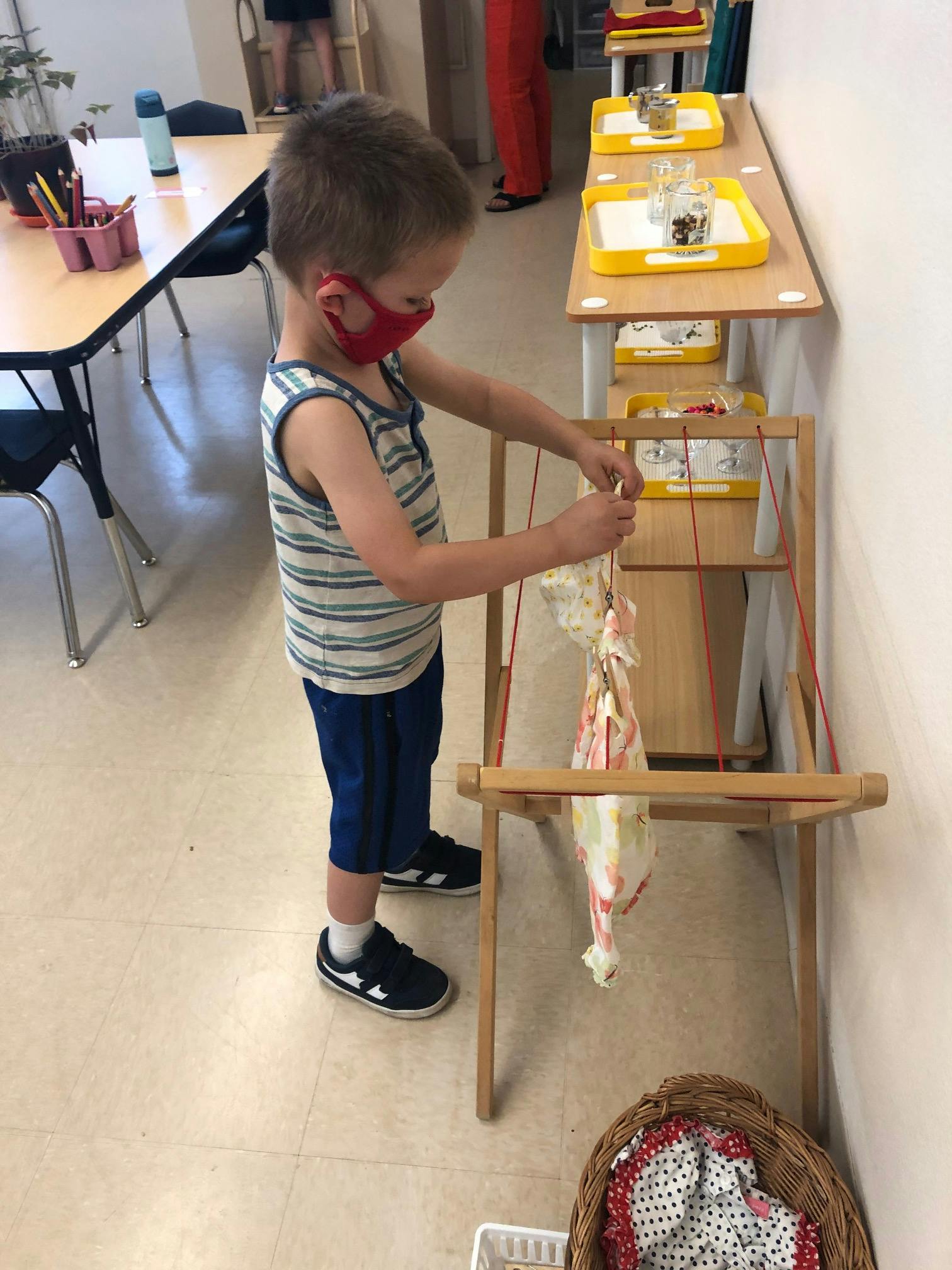 Child in a mask working with a wooden frame and fabric