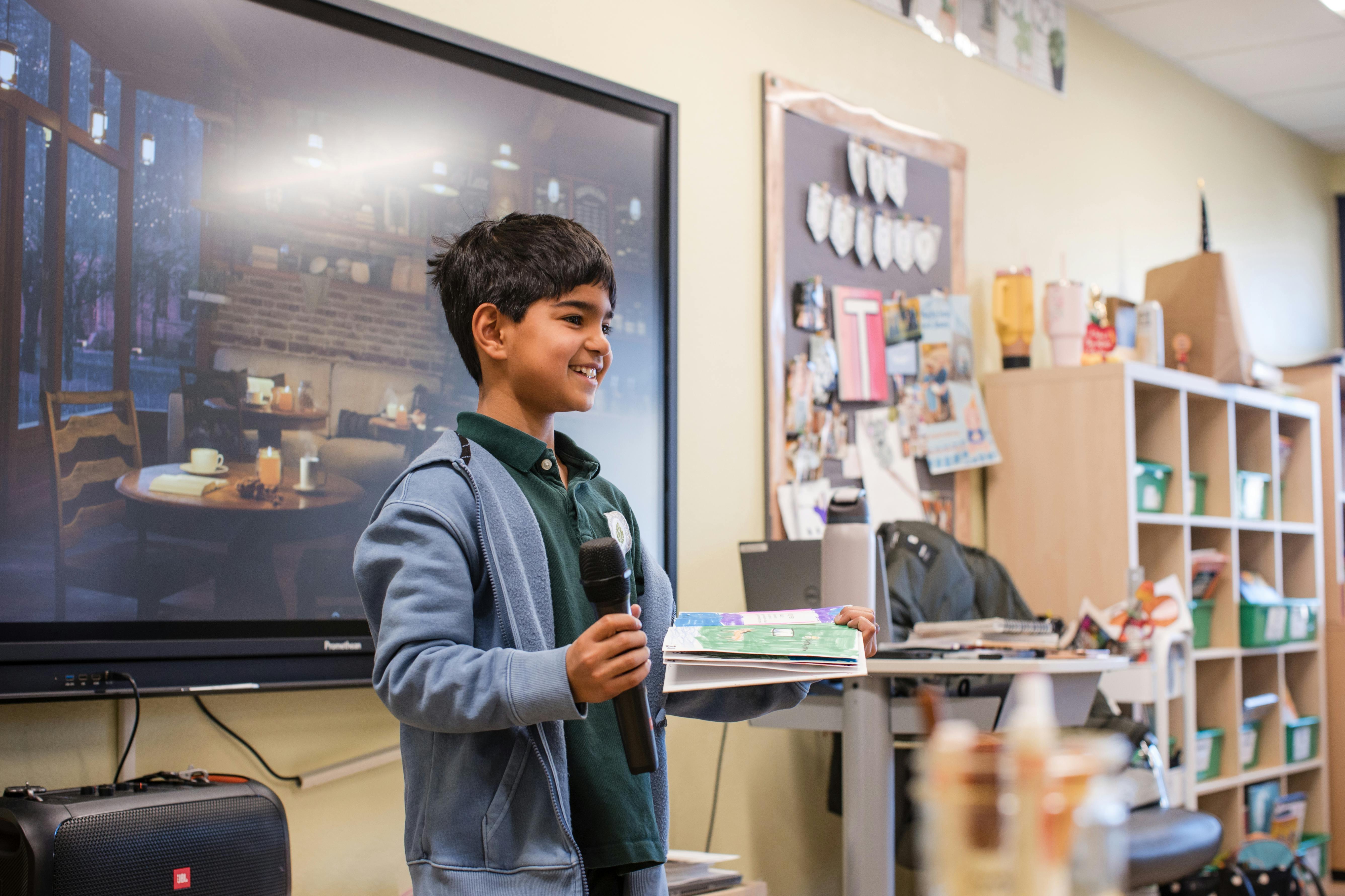 Child holding a microphone in front of a large screen