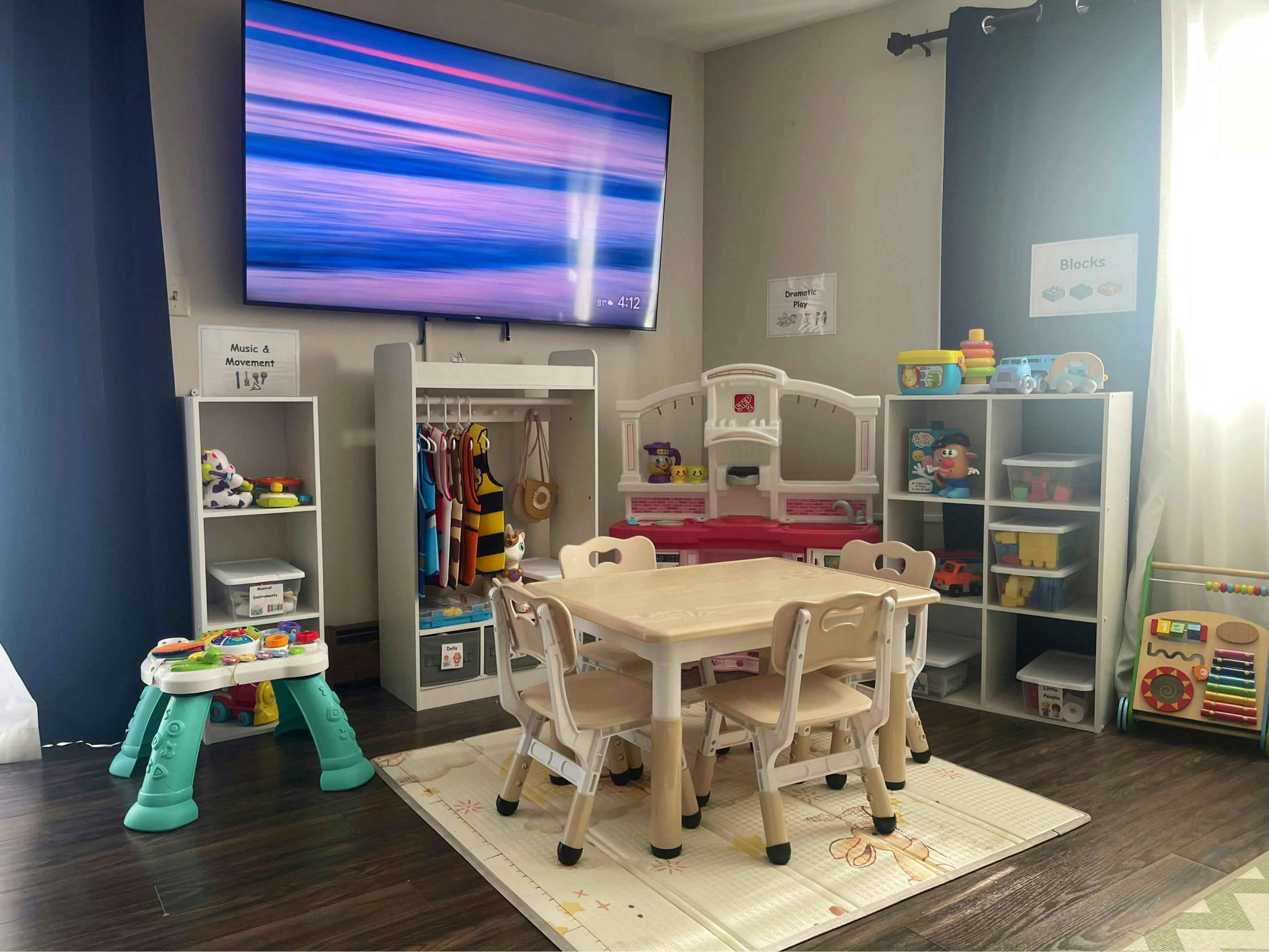 Children's play area with a small table and chairs, shelves with toys, and a TV