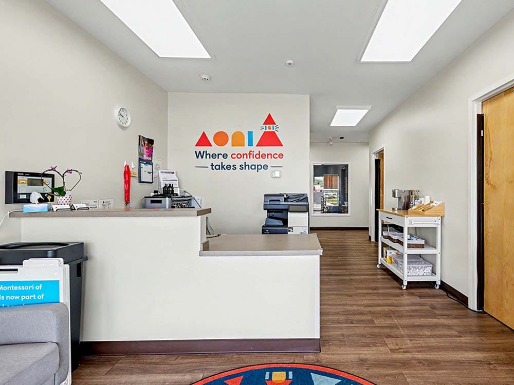 Montessori classroom reception desk with a sign that reads, "Where confidence takes shape"