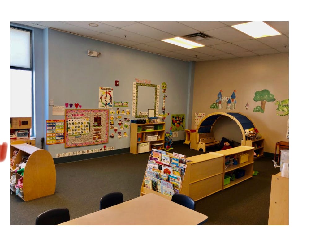 Empty classroom with tables, shelves, and a play tunnel