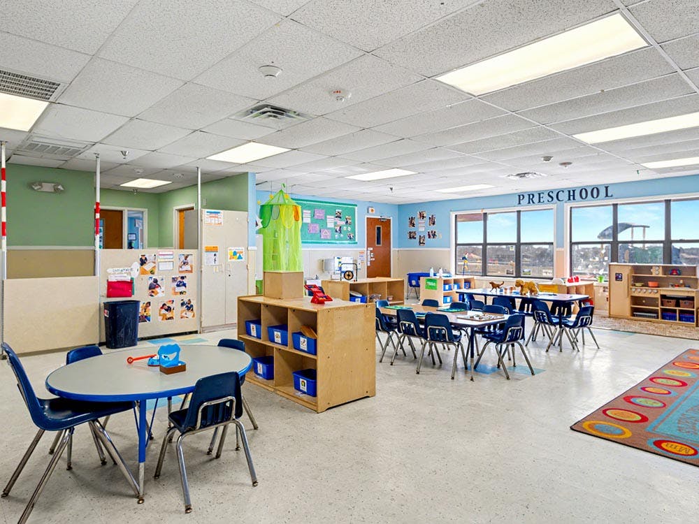 Empty preschool classroom with small tables and chairs