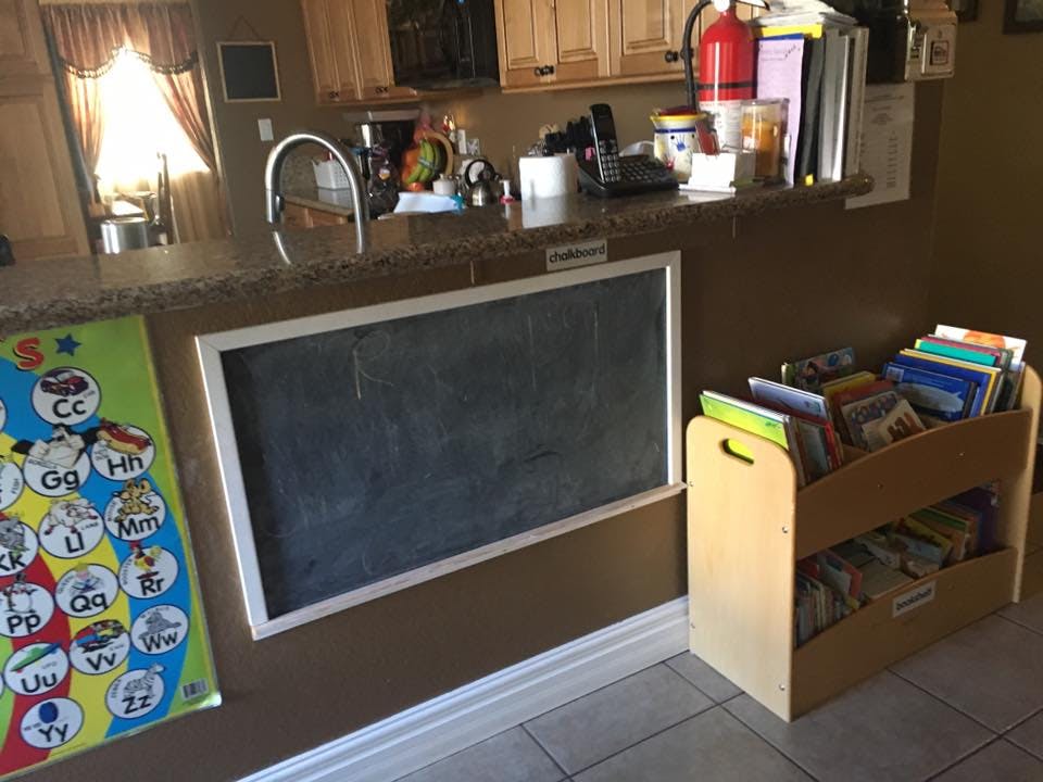 Chalkboard and book rack in a room with a kitchen counter