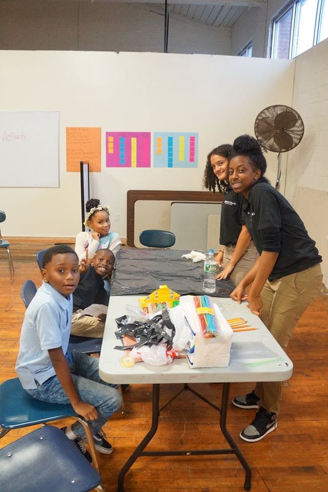 People and children gathered around a table with craft supplies