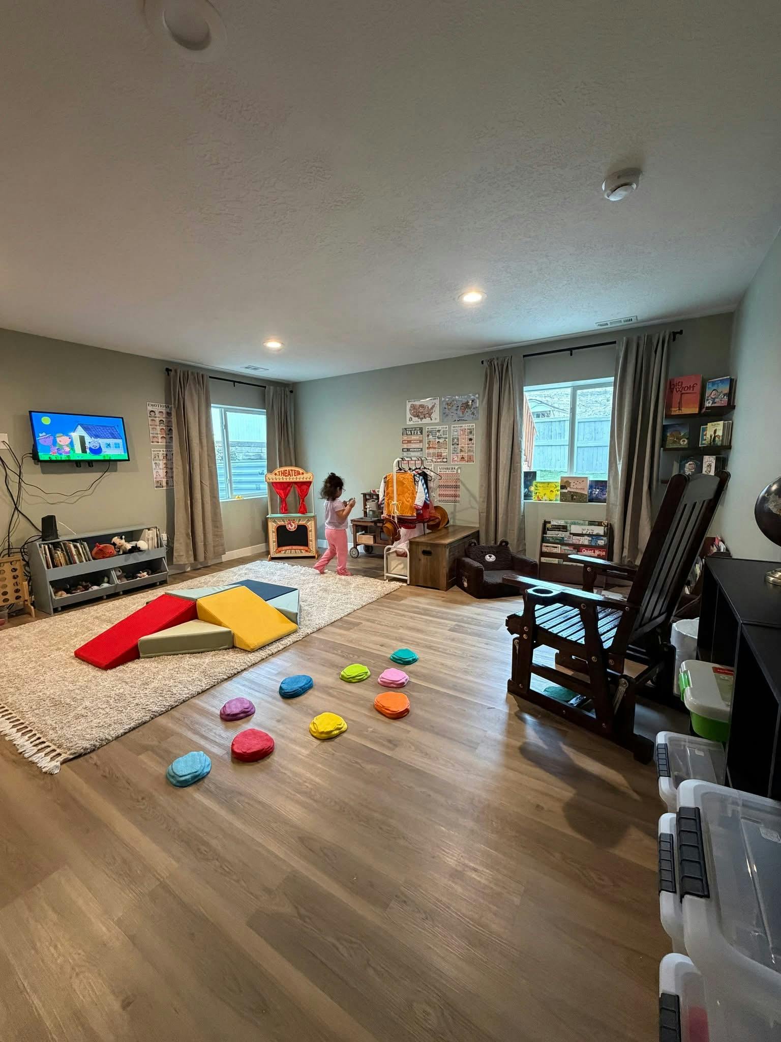 Child playing in a room with a TV, windows, and play equipment