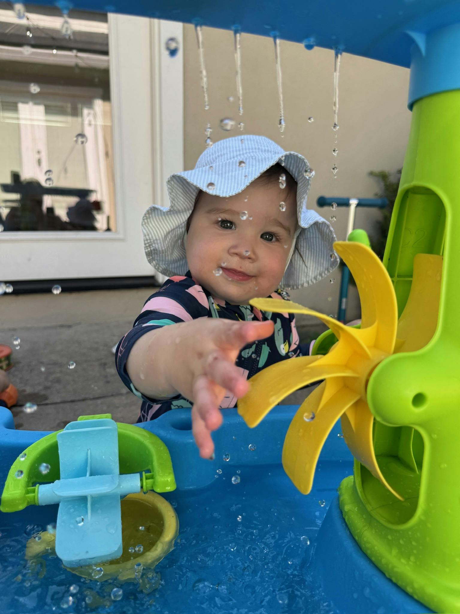 Child in a sun hat playing with a water table