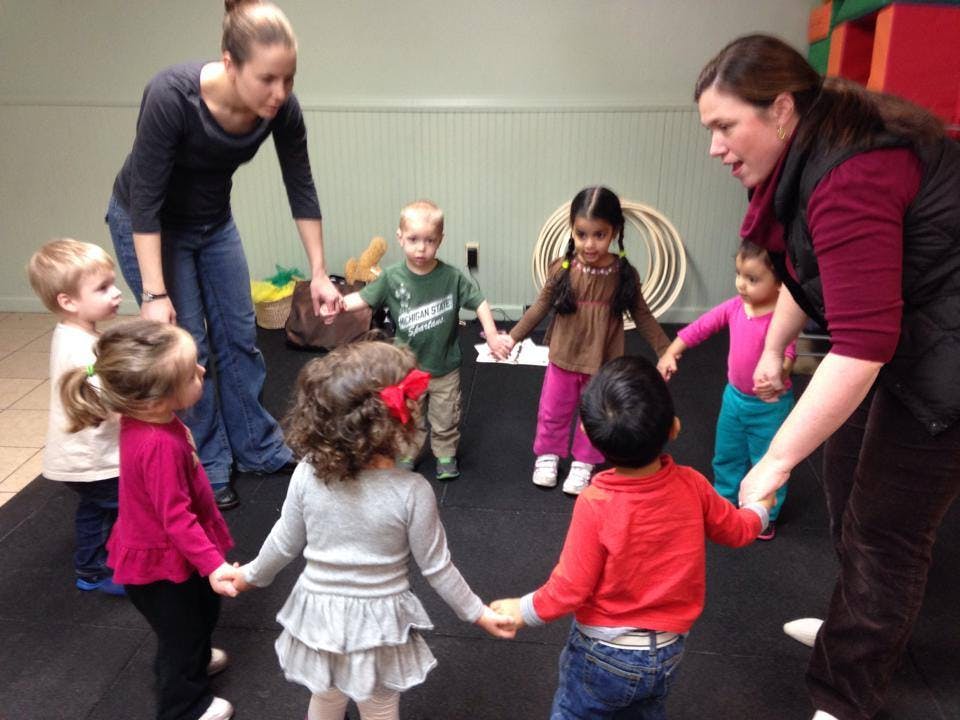 Two people holding hands with a group of children in a circle