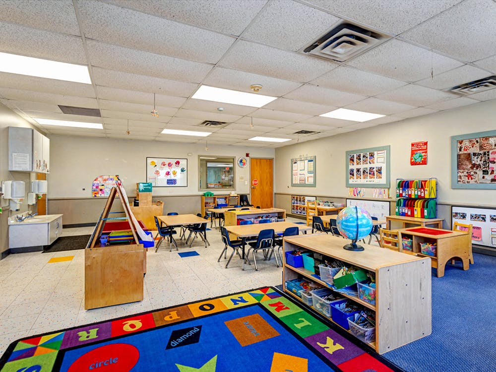 Empty classroom with small tables, chairs, and learning materials