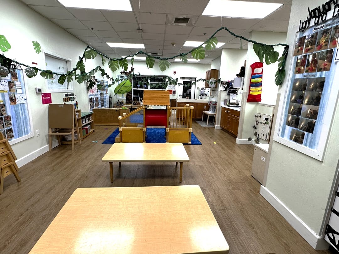Empty classroom with small tables and a play structure