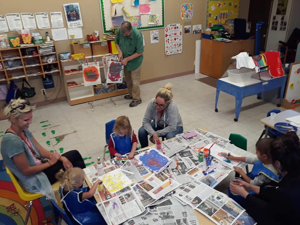 Adults and children doing art projects in a classroom
