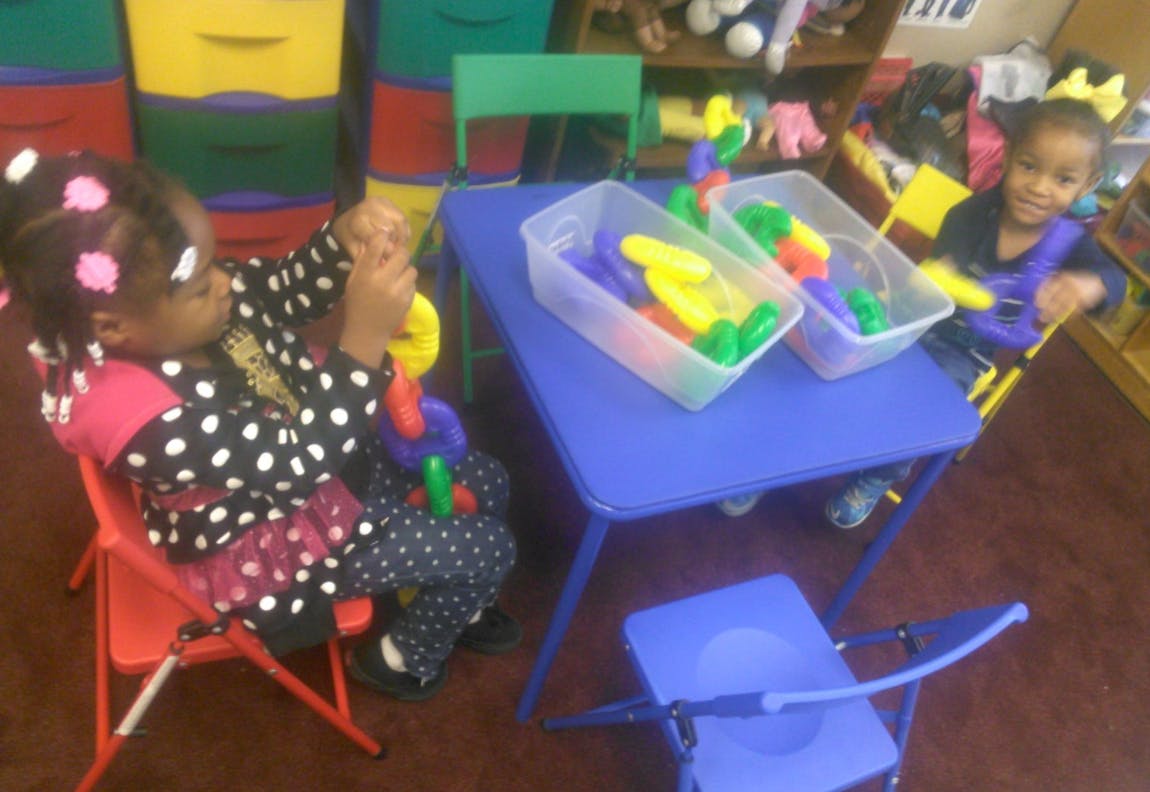 Two children playing with colorful linking toys at a blue table