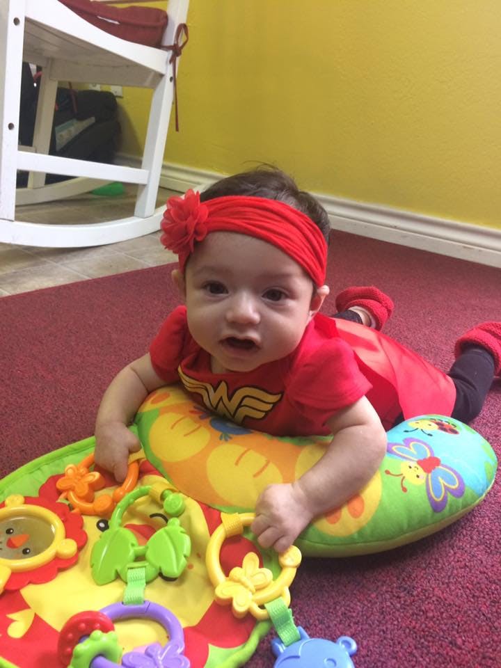 Child in a red Wonder Woman outfit on a playmat