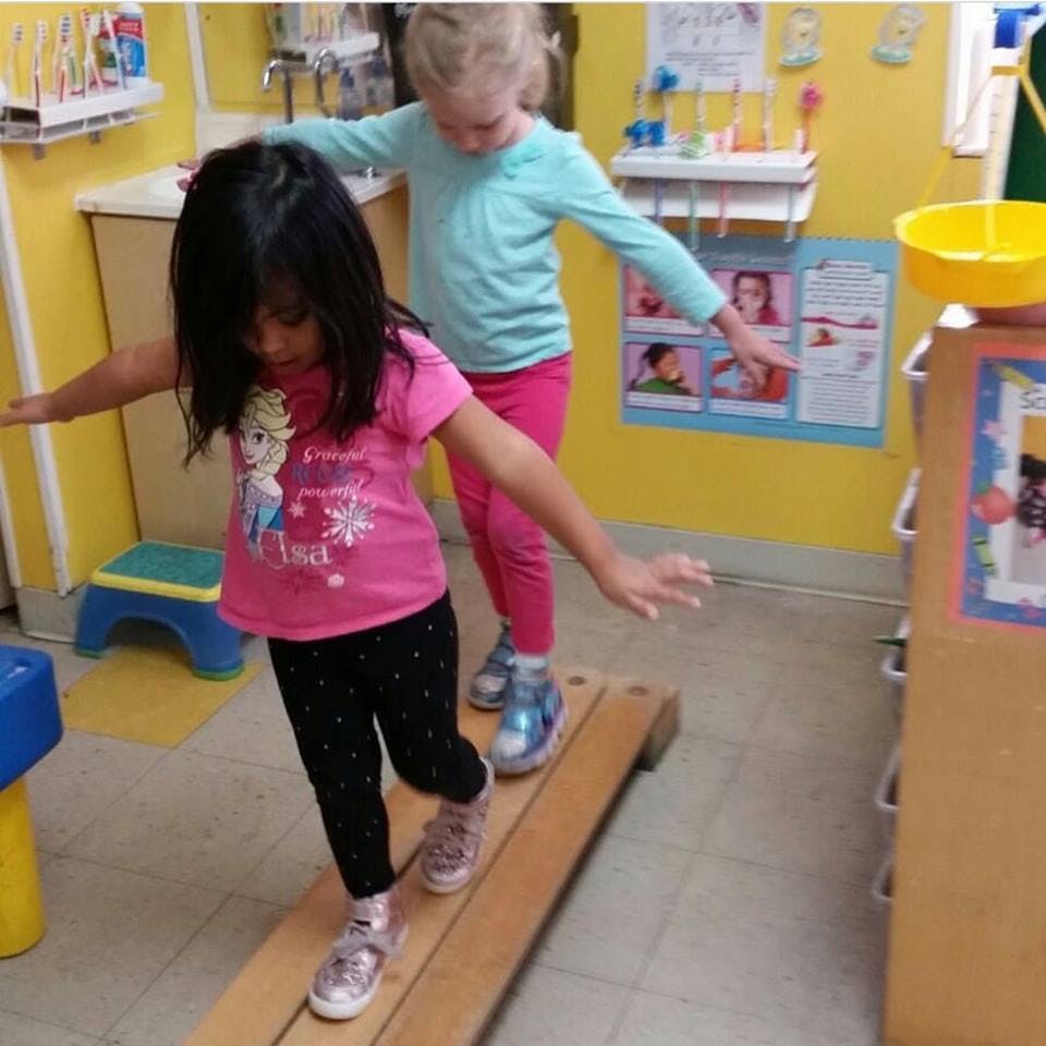 Two children balancing on a wooden beam