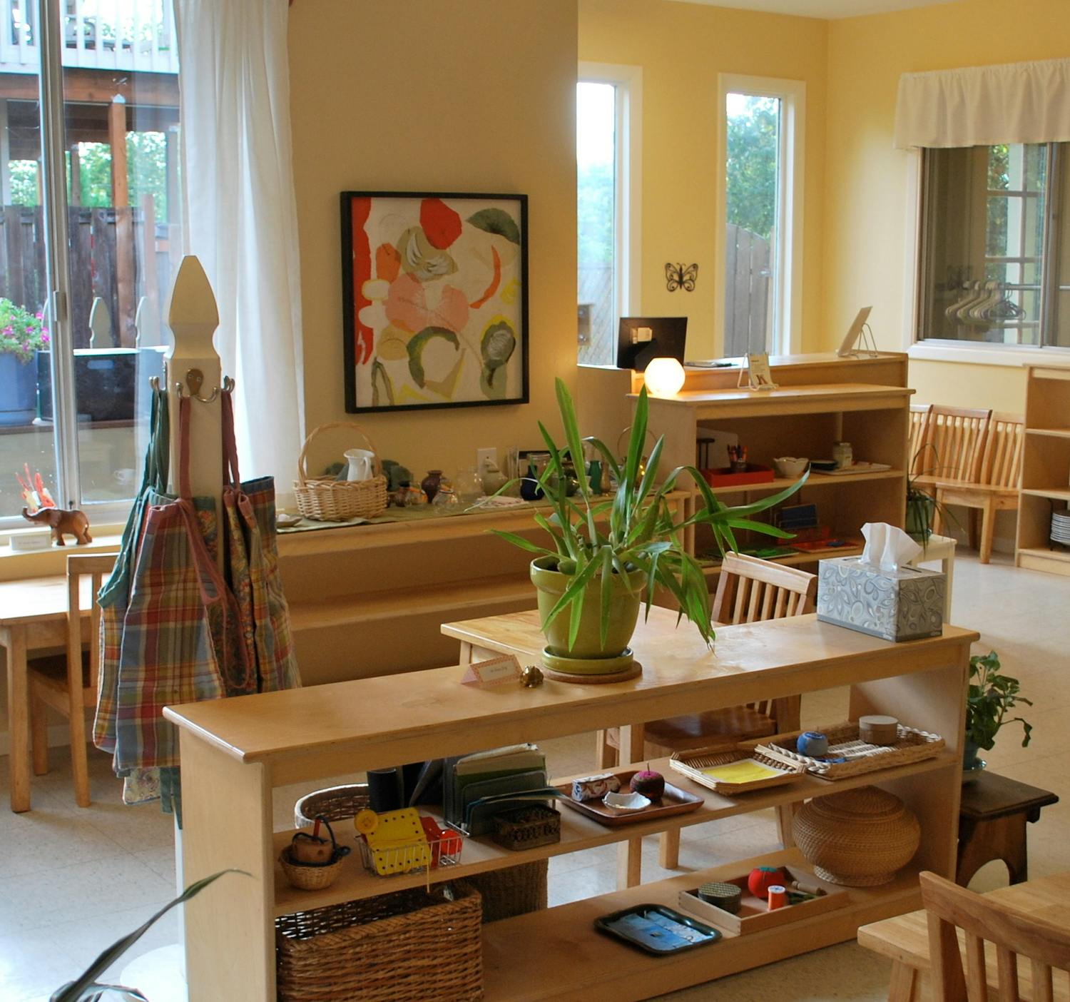 Classroom with wooden furniture, shelves, and plants