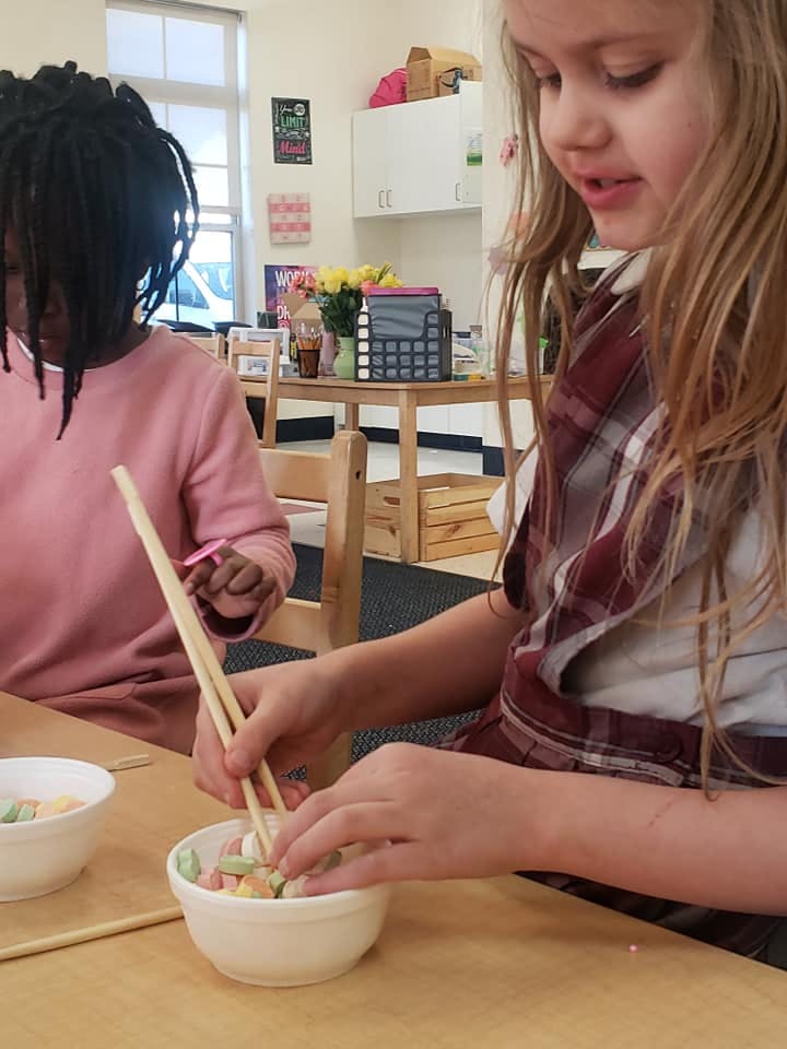 Child using chopsticks to pick up items from a bowl