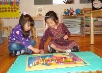 Two children playing with a puzzle on the floor