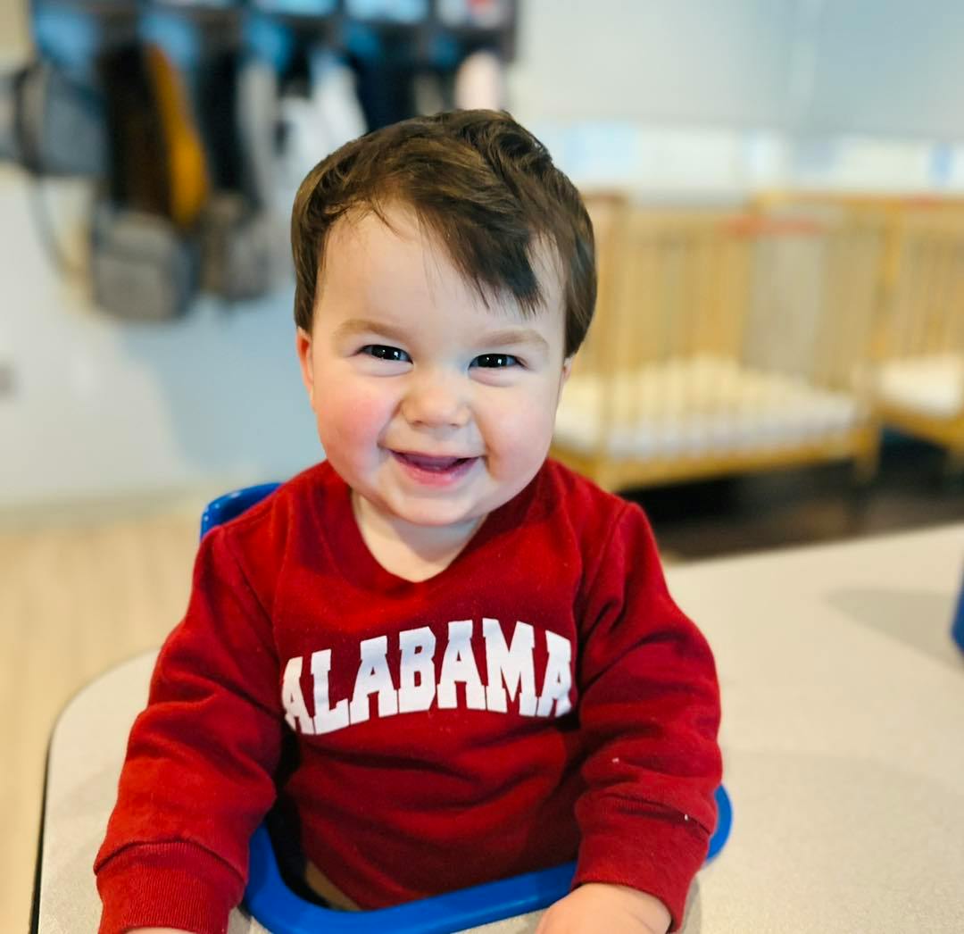 Child in red Alabama shirt sitting in a high chair