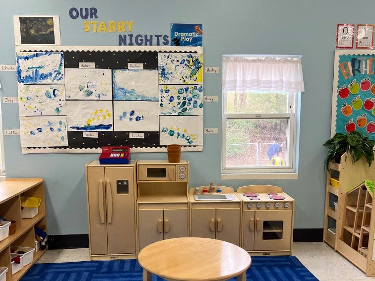 Classroom wall with art display, play kitchen set, and window