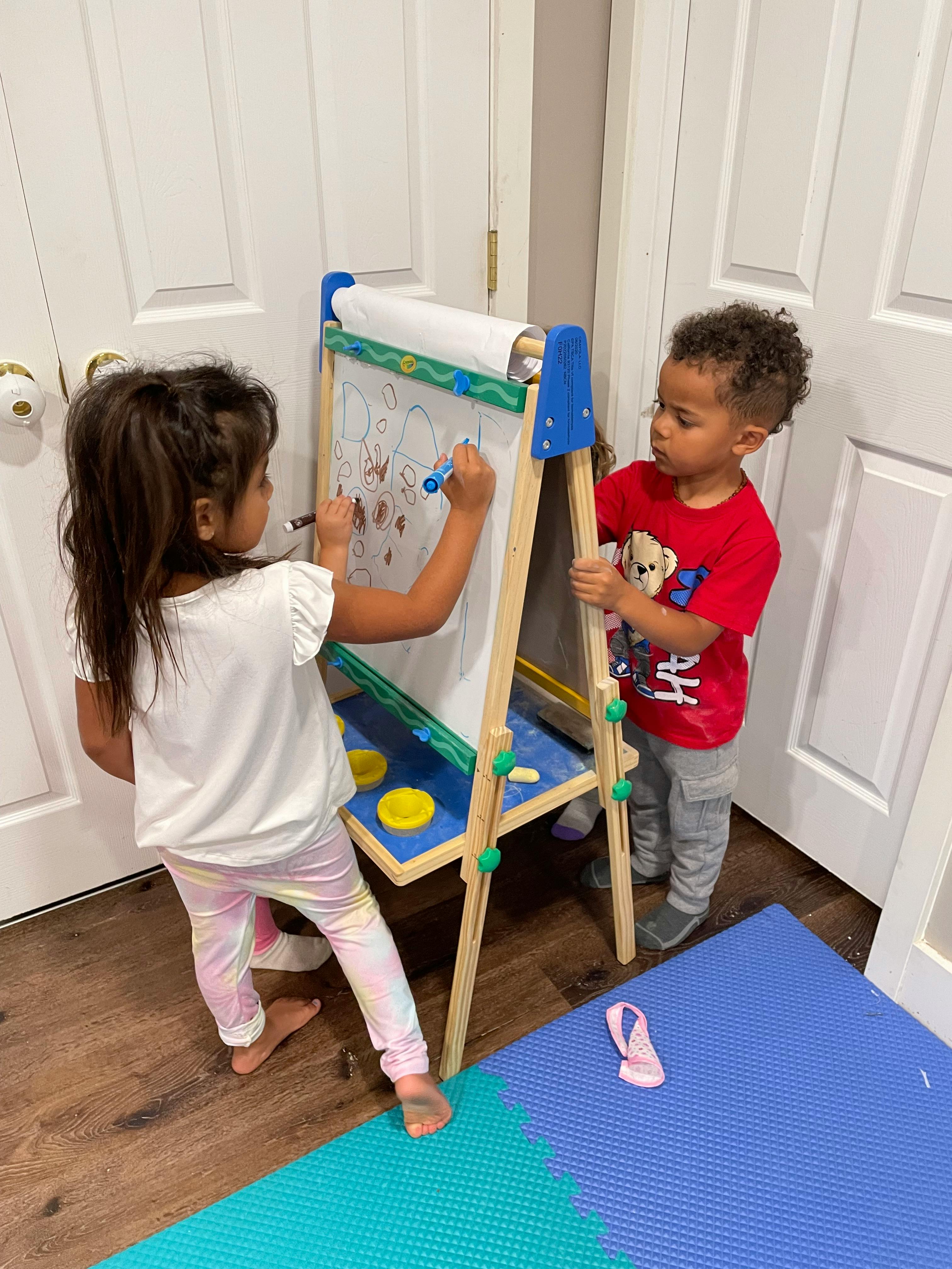 Two children drawing on an easel